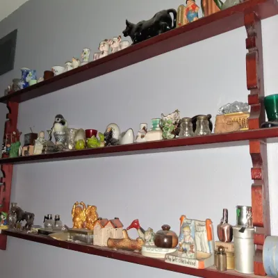 Sale Photo Thumbnail #56: Three-tier wooden wall shelf displaying an assortment of vintage knick-knacks, figurines, and salt and pepper shakers.