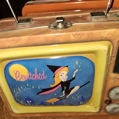 Sale Photo Thumbnail #135: Vintage Bewitched metal lunchbox shaped like a retro television set, featuring the animated Samantha Stephens character on the front screen.