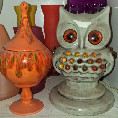 Sale Photo Thumbnail #16: Vintage 1970s ceramic owl lamp with amber glass insert beads, shown alongside a vibrant orange and green drip-glaze lidded pedestal jar.