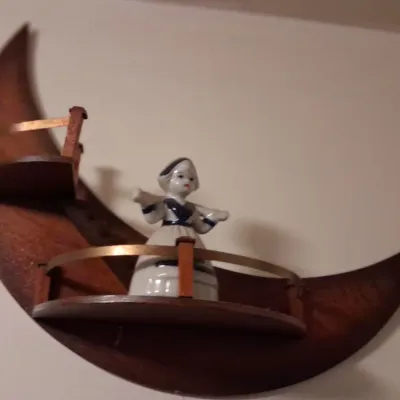 Sale Photo Thumbnail #65: Vintage mid-century crescent moon wooden wall shelf with a small ceramic Dutch girl figurine.