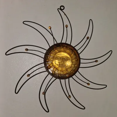Sale Photo Thumbnail #5: Vintage metal and amber glass sunburst wall hanging, featuring a molded glass sun face center surrounded by curved wire rays.