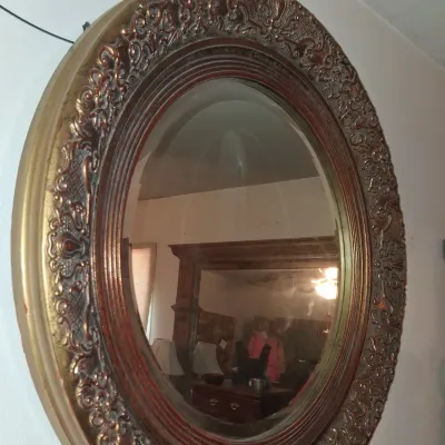 Sale Photo Thumbnail #29: Ornate oval wall mirror featuring a heavily detailed, gilded frame with scrollwork and a beaded inner border.