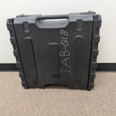 Sale Photo Thumbnail #288: Heavy-duty molded black plastic equipment carrying case with integrated handle, marked with handwritten identification code 'IAB-018'.