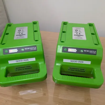Sale Photo Thumbnail #229: Pair of Newcastle Systems green portable power pack batteries, labeled "GOOD 2026" with integrated carrying handles.