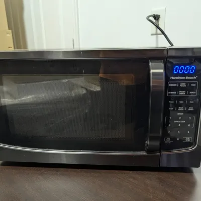 Sale Photo Thumbnail #72: Hamilton Beach countertop microwave oven in a black and stainless steel finish, featuring a digital display and touch control panel.
