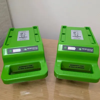 Sale Photo Thumbnail #228: Pair of Newcastle Systems green portable power pack batteries, showing light indicators and integrated carrying handles.