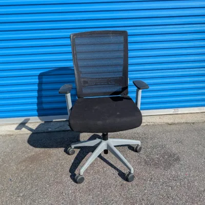 Sale Photo Thumbnail #59: Modern black mesh-back office chair with adjustable armrests and a grey five-star rolling base.