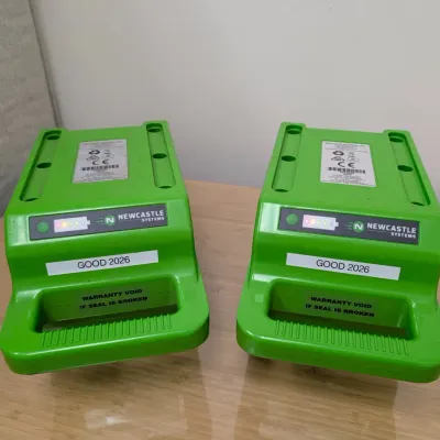 Sale Photo Thumbnail #227: Pair of Newcastle Systems green portable power pack batteries, showing active charge indicator lights and labeled "GOOD 2026".