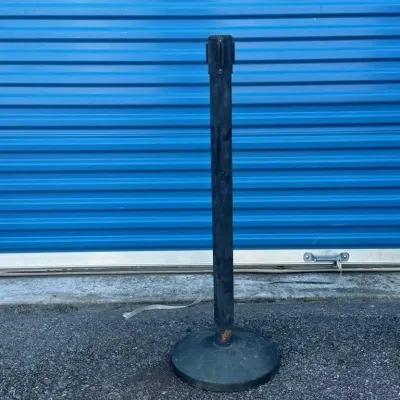Sale Photo Thumbnail #52: Black metal stanchion with a retractable belt mechanism, showing some wear and scuffs from use.