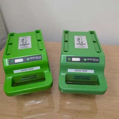 Sale Photo Thumbnail #234: Pair of Newcastle Systems green portable power pack batteries, labeled "GOOD 2026" and showing active charge indicator lights.