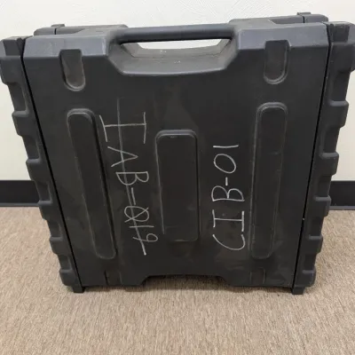 Sale Photo Thumbnail #292: Heavy-duty black molded plastic equipment carrying case with integrated handle, marked with white handwritten identification codes.