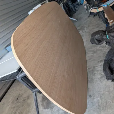 Sale Photo Thumbnail #42: Large oval conference table with a light wood grain laminate top and black metal legs, shown tilted on its side in a storage unit.