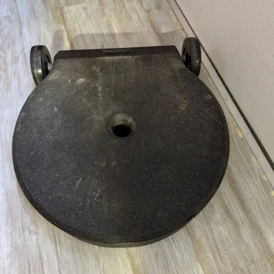 Sale Photo Thumbnail #76: Heavy-duty black composite rolling sign stand base, showing some surface wear and dust from outdoor use.