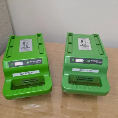 Sale Photo Thumbnail #235: Two Newcastle Systems green portable power pack batteries, showing light indicators and labeled "GOOD 2026".