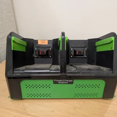 Sale Photo Thumbnail #224: PowerCharge Station dual-bay battery charger in black and green plastic housing, showing some surface dust and wear.