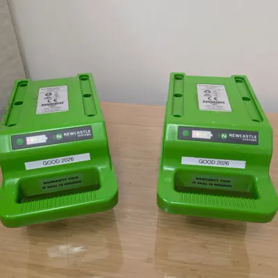 Sale Photo Thumbnail #236: Pair of Newcastle Systems green portable power pack batteries, labeled "GOOD 2026" and showing active charge indicator lights.