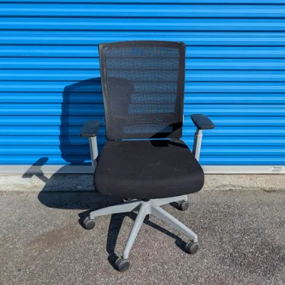 Sale Photo Thumbnail #58: Modern black mesh-back office chair with a padded fabric seat, adjustable armrests, and a grey five-star rolling base.