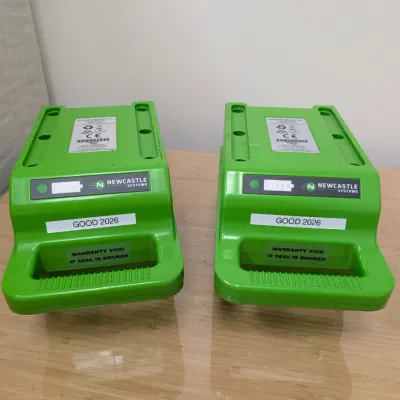 Sale Photo Thumbnail #231: Pair of Newcastle Systems green portable power pack batteries, labeled "GOOD 2026" with integrated carrying handles.