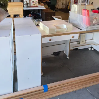 Sale Photo Thumbnail #93: White laminate sewing cabinet with a drop-down platform, wooden trim, and matching storage towers, shown in a garage setting.
