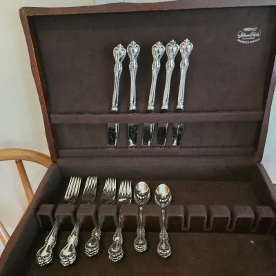 Sale Photo Thumbnail #69: Partial set of vintage silver-plated flatware with ornate handles, housed in a brown Pacific Silver Cloth anti-tarnish wooden storage chest.