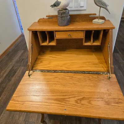 Sale Photo Thumbnail #57: Vintage oak secretary desk with a drop-front writing surface, interior cubbies, and a small drawer, styled with decorative wooden shorebird figurines.