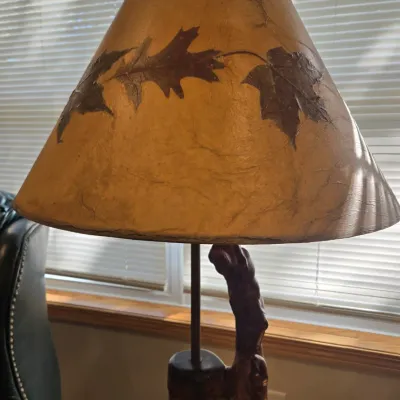 Sale Photo Thumbnail #40: Rustic table lamp featuring a natural wood branch base and a textured parchment shade decorated with pressed autumn leaves.