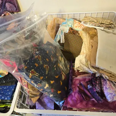Sale Photo Thumbnail #21: Assorted fabric scraps and quilting quarters in various patterns and colors, organized in a white wire basket.