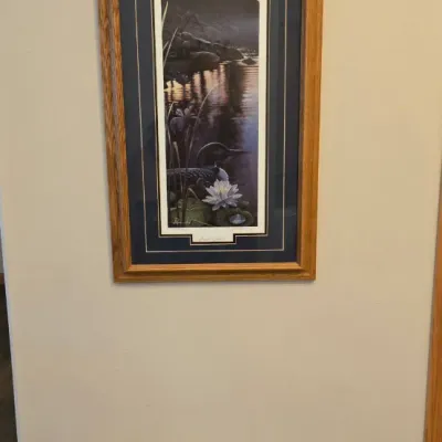 Sale Photo Thumbnail #76: Two framed art prints in oak frames, featuring a vertical wilderness scene with a loon and a horizontal cottage landscape.
