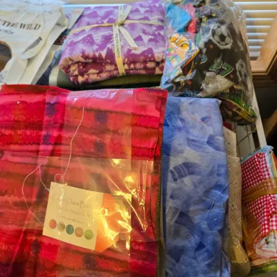 Assorted quilting fabric bundles and scraps, including a Color Daze Batiks pack by Moda and a purple tie-dye pattern bundle.