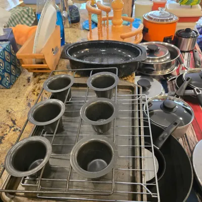 Sale Photo Thumbnail #74: Assorted kitchenware including a popover pan, baking sheets, a speckled enamel roasting pan, and various pots and pans.