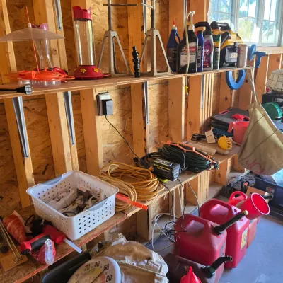 Sale Photo Thumbnail #101: Assorted garage and garden items, including jack stands, bird feeders, extension cords, gas cans, and a large outdoor thermometer.