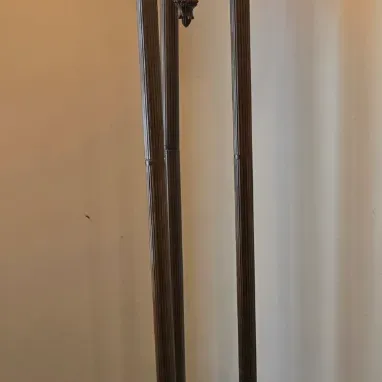 Sale Photo Thumbnail #47: Neoclassical-style torchiere floor lamp featuring a dark bronze-finished metal frame with three fluted columns, a glowing amber glass shade, and a matching illuminated accent urn.