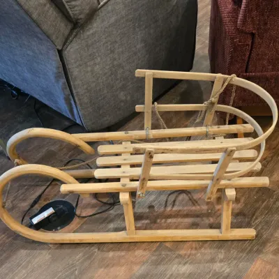 Vintage wooden child's pull sled with bentwood runners and a slatted seat, showing natural wear from age.