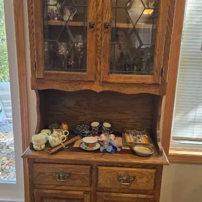 Sale Photo Thumbnail #49: Vintage oak hutch featuring leaded glass upper cabinet doors, a central display shelf, and lower storage drawers and cabinets.