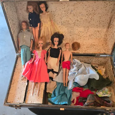 Sale Photo Thumbnail #115: Vintage Barbie, Ken, and family dolls from the 1960s, displayed inside a vintage doll trunk with assorted doll clothing.