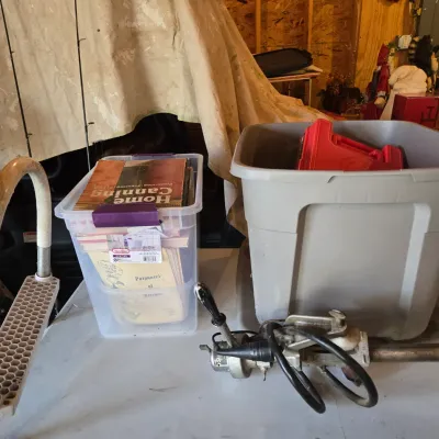 Sale Photo Thumbnail #81: Assorted garage items including a clear plastic bin filled with vintage canning and recipe books, a large grey storage tote, and a vintage trolling motor.