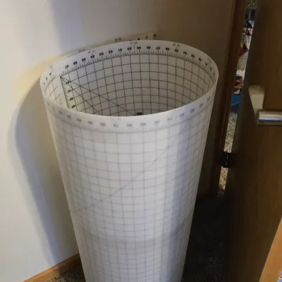 Large, flexible plastic cutting mat with grid lines and measurements, rolled up for storage.