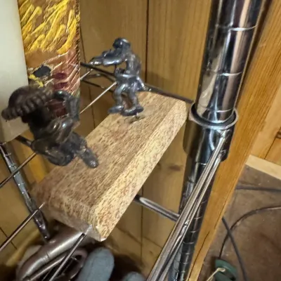 Sale Photo Thumbnail #127: Two small cast metal figurines depicting musicians, mounted on a rustic wooden block.