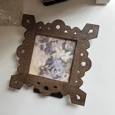 Sale Photo Thumbnail #177: Small square cast iron picture frame with an ornate, openwork geometric border, housing a floral print.