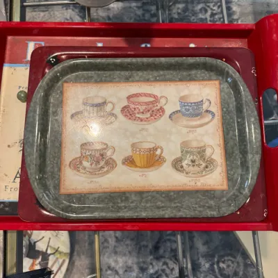 Sale Photo Thumbnail #264: Small metal serving tray featuring an illustration of six vintage teacups and saucers, stacked on top of larger red trays.