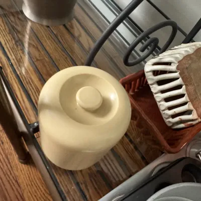 Sale Photo Thumbnail #327: Vintage beige ceramic canister with lid, shown alongside various kitchenware items on a metal baker's rack.