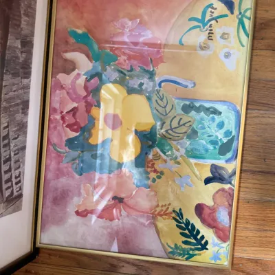 Sale Photo Thumbnail #234: Framed watercolor print featuring a vibrant floral still life in shades of yellow, pink, and green, housed in a simple gold-tone metal frame.