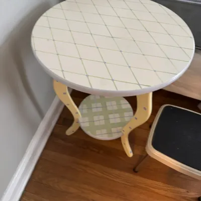 Sale Photo Thumbnail #213: Whimsical hand-painted wooden side table featuring a diamond-patterned top, curved yellow legs with purple dots, and a plaid lower shelf.