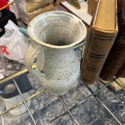 Sale Photo Thumbnail #336: Handmade studio pottery pitcher with a speckled white glaze, displayed next to vintage leather-bound books.