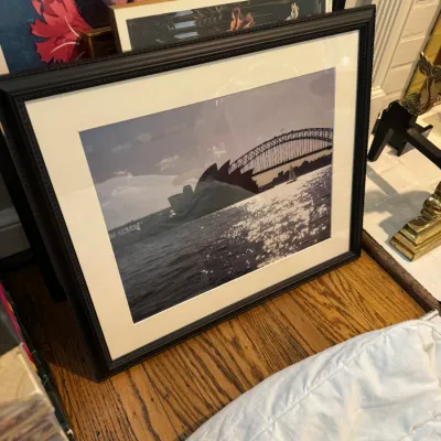 Sale Photo Thumbnail #247: Framed photograph of the Sydney Opera House and Harbour Bridge, matted in white and set in a dark textured frame.