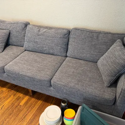 Sale Photo Thumbnail #28: Contemporary three-seat sofa upholstered in a textured gray tweed fabric, featuring tapered wooden legs and matching throw pillows.