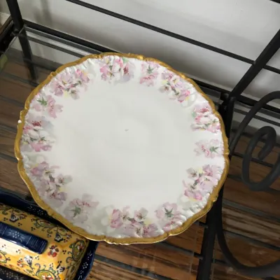 Sale Photo Thumbnail #320: Vintage porcelain serving plate featuring a scalloped gold-gilt rim and a delicate pink floral border.