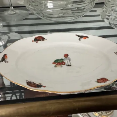 Sale Photo Thumbnail #346: Vintage oval porcelain dish featuring a central illustration of a child with a frog on a mushroom, bordered by various insects and birds with a gold-gilded rim.