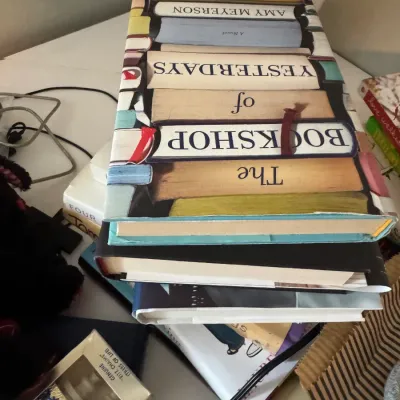 Sale Photo Thumbnail #219: A stack of hardcover books, featuring "The Bookshop of Yesterdays" by Amy Meyerson on top, displayed alongside other household items.