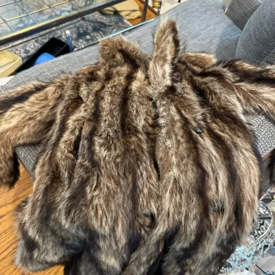Sale Photo Thumbnail #54: Vintage long-haired fur coat, possibly raccoon or fox, featuring vertical pelts in shades of brown, grey, and black.